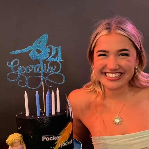 Smiling young woman with a 21st birthday cake decorated with waves, shells and a Kombi van.